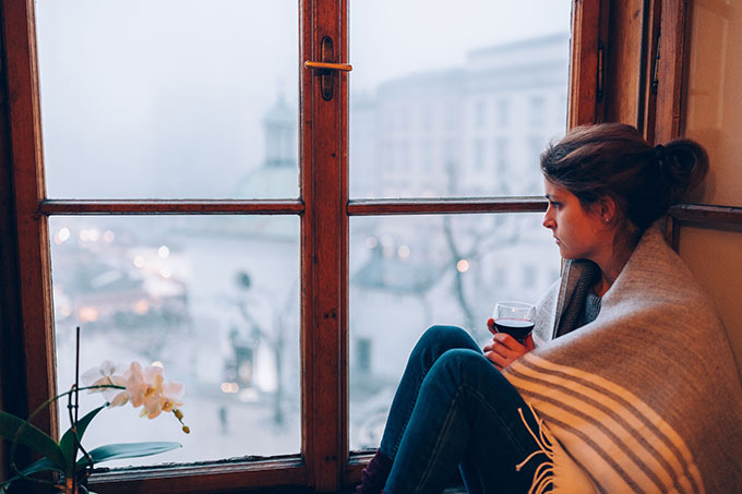 woman sitting drinking wine looking out window