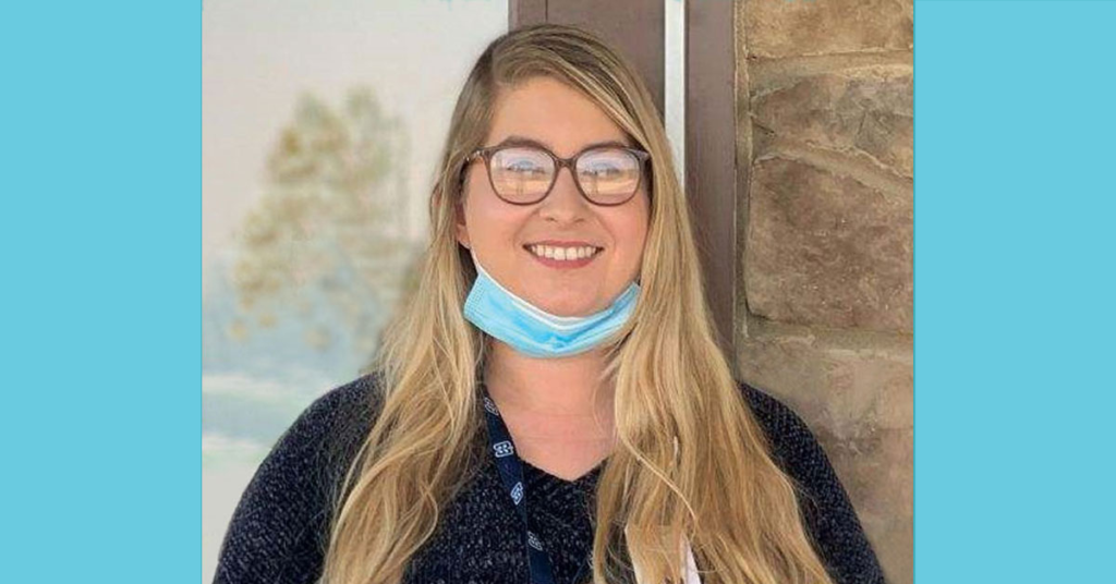 Smiling young woman with a medical mask pulled down around her neck. 